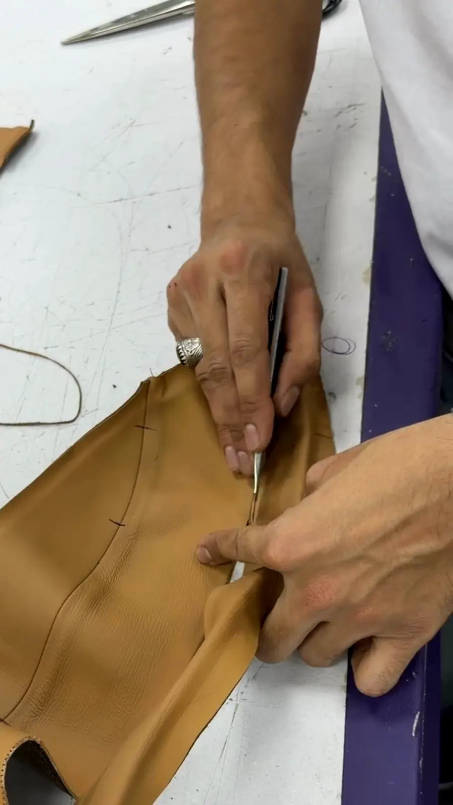 Hands cutting and skiving leather by hand in the HM Atelier workshop